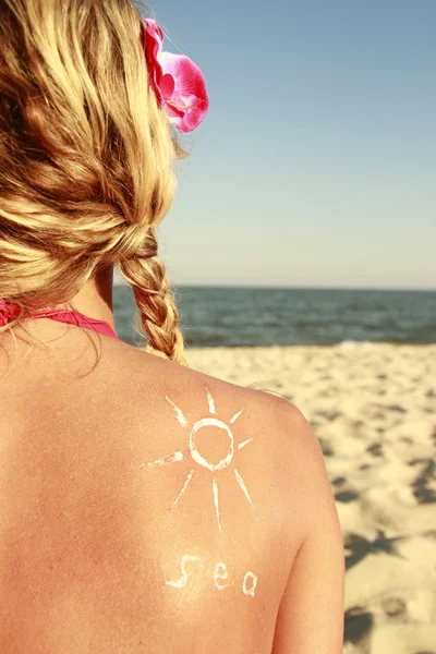 Sun cream on the female back on the beach — Stock Photo, Image