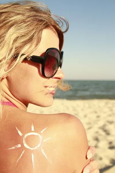 Sun cream on the female back on the beach — Stock Photo, Image