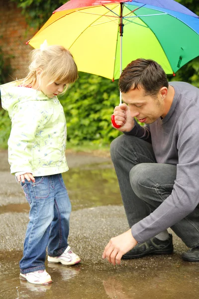 Girl with an umbrella in the rain with his father — Stock Photo, Image