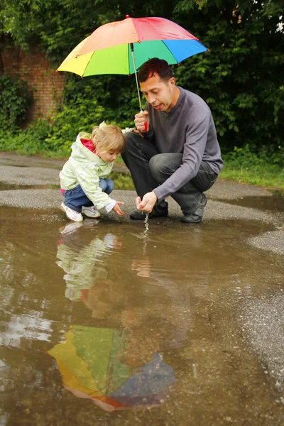 Dívka s deštníkem v dešti se svým otcem — Stock fotografie