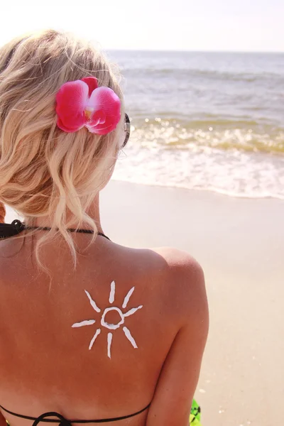 Sun cream on the female back on the beach — Stock Photo, Image
