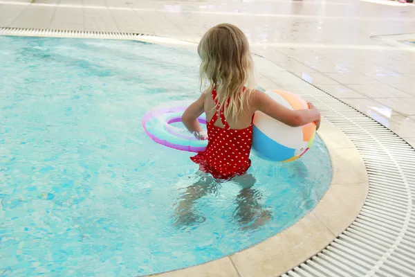 Liten flicka i vatten poolen med en boll — Stockfoto