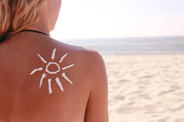 Crema solar en la espalda femenina en la playa — Foto de Stock