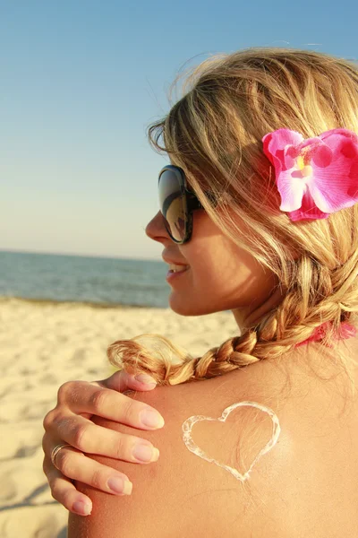 Heart of the cream on the female back on the beach — Stock Photo, Image