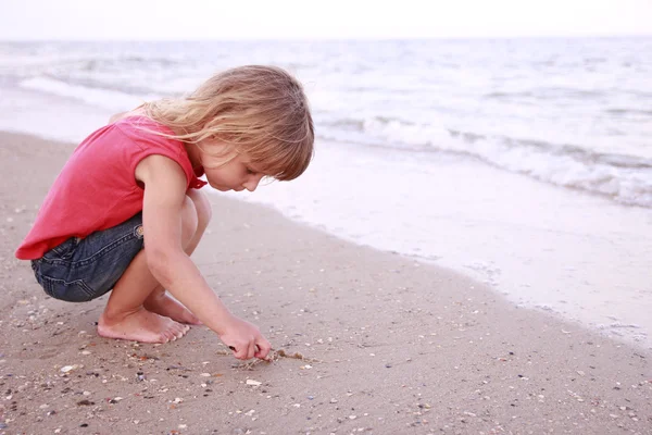 Fille dessine un soleil dans le sable sur la plage — Photo