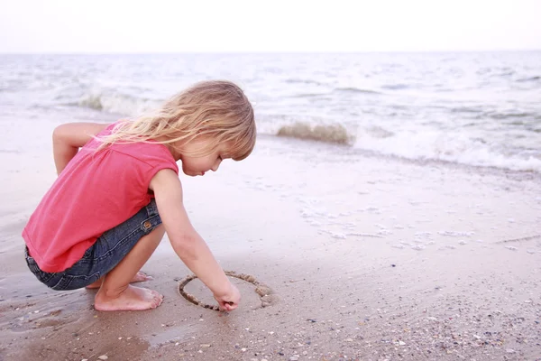 Menina desenha um sol na areia na praia — Fotografia de Stock