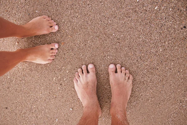 Älskande par fötter i sanden — Stockfoto
