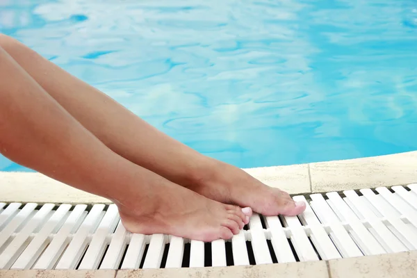 Vrouwelijke benen in het zwembad water — Stockfoto