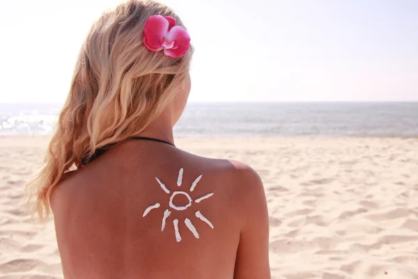 Crema solare sulla schiena femminile sulla spiaggia — Foto Stock