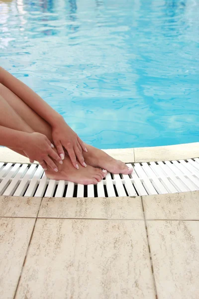 Vrouwelijke benen in het zwembad water — Stockfoto