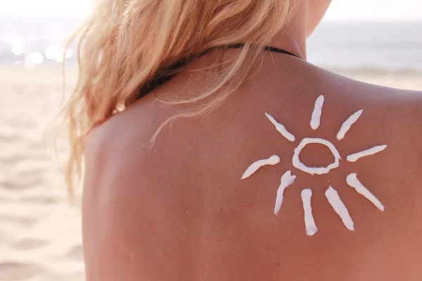 Sun cream on the female back on the beach — Stock Photo, Image