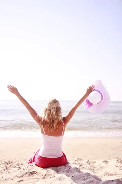 Het meisje met de hoed op het strand — Stockfoto