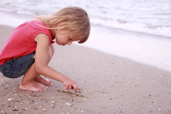 Girl draws a sun in the sand on the beach — Stock Photo, Image