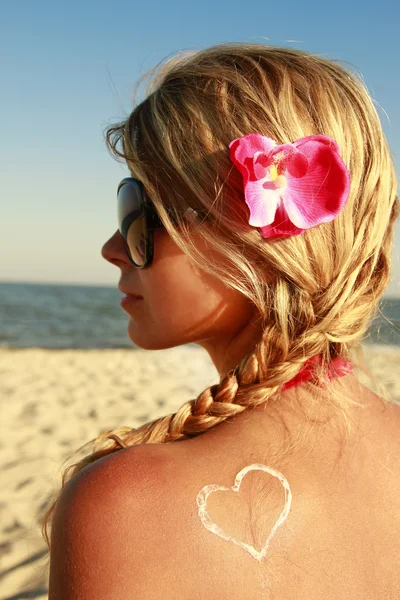 Corazón de la crema en la espalda femenina en la playa —  Fotos de Stock