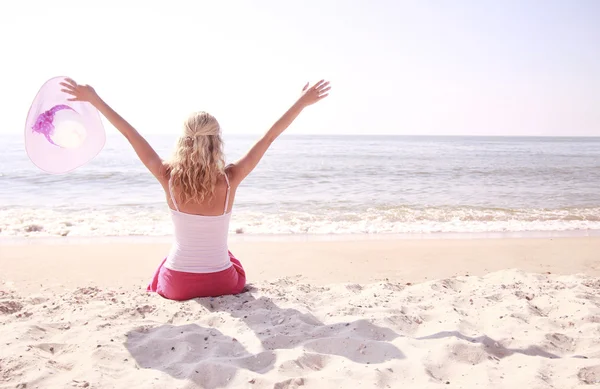 Счастливая девушка в шляпе на пляже — стоковое фото