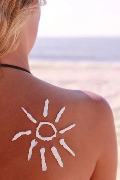 Sun cream on the female back on the beach — Stock Photo, Image