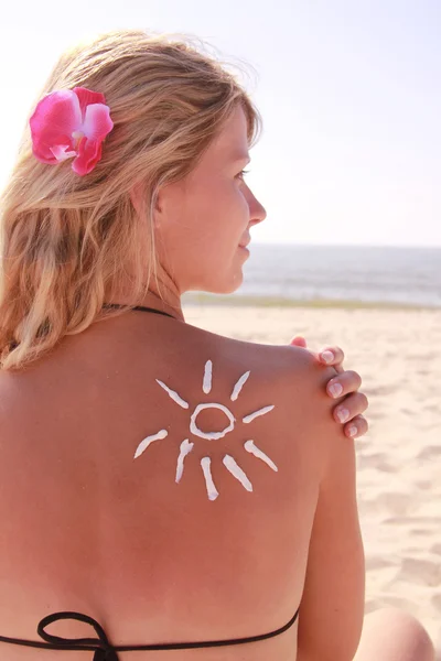 Crema solar en la espalda femenina en la playa — Foto de Stock