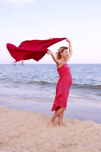 Вагітна жінка з шарфом на пляжі — стокове фото