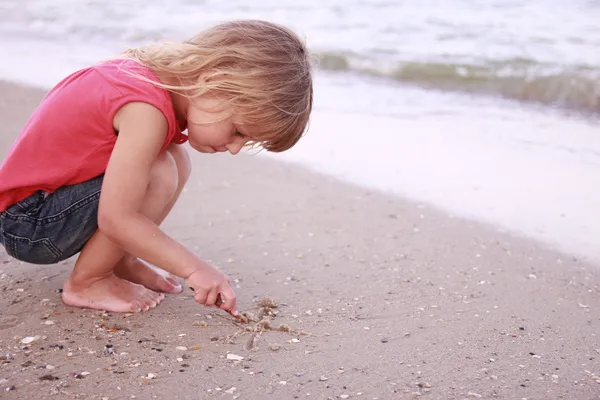 Little girl draws a sun in the sand — Stock Photo, Image