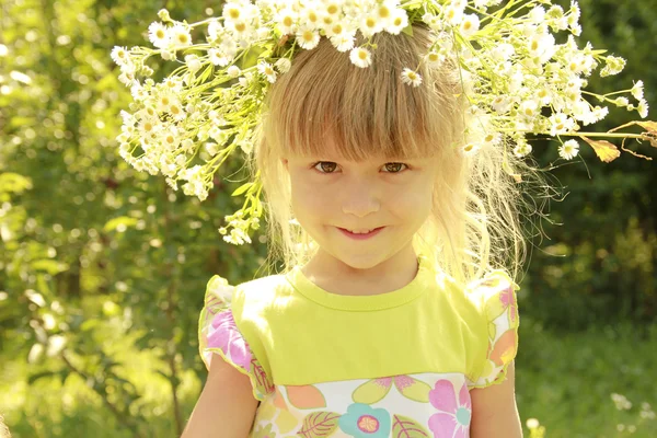 Hermosa niña en una corona de flores en la naturaleza — Foto de Stock