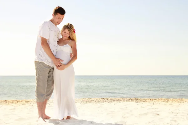 Беременная пара влюблена на пляже — стоковое фото
