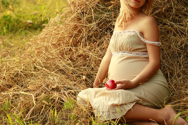 Zwangere vrouw op de natuur in de buurt van de hooibergen — Stockfoto