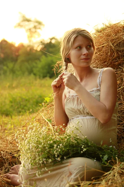 Pregnant woman on nature near the haystacks — Stock Photo, Image