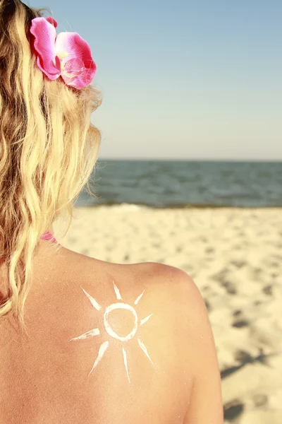 Crema solare sulla schiena femminile sulla spiaggia — Foto Stock