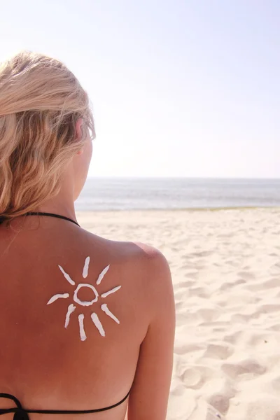 Crema solar en la espalda femenina en la playa — Foto de Stock