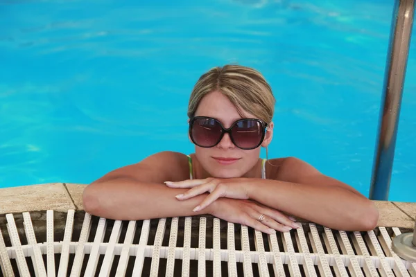 Menina na piscina de água em óculos de sol — Fotografia de Stock