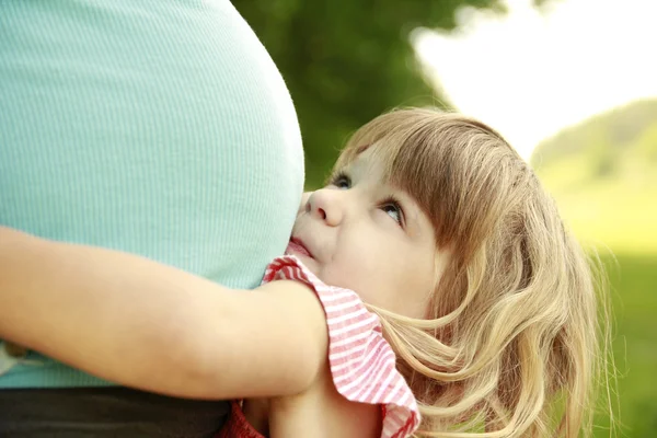 Niña cerca del vientre de su madre embarazada en la naturaleza — Foto de Stock