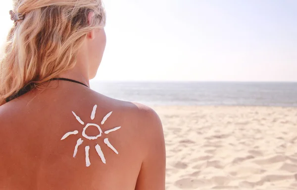 Van zon crème op de vrouwelijke rug op het strand — Stockfoto