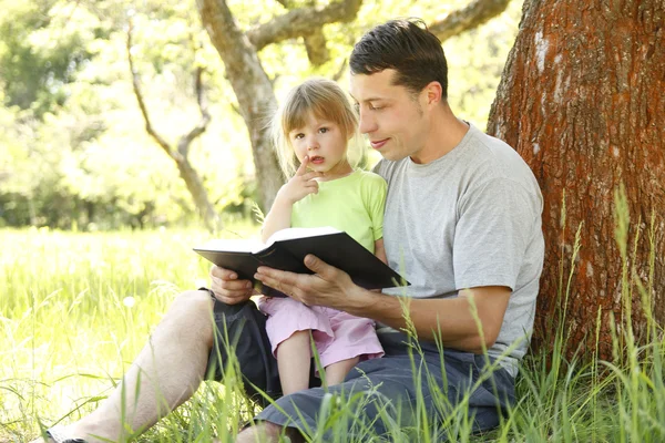 Jovem pai com sua filhinha lê a Bíblia — Fotografia de Stock