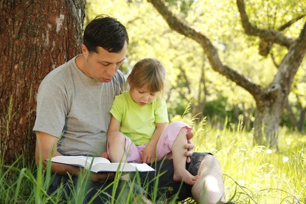 Padre joven con su pequeña hija lee la Biblia — Foto de Stock