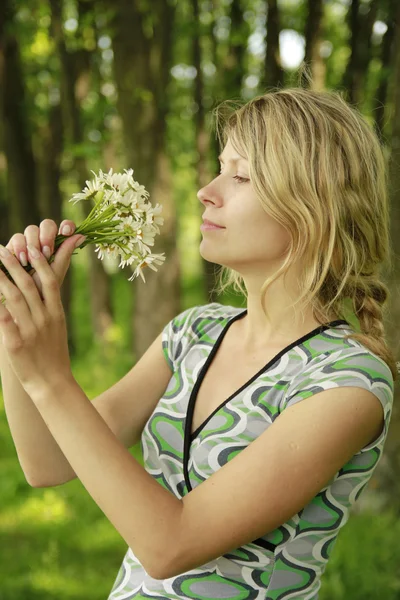 Ung flicka med en bukett blommor i naturen — Stockfoto