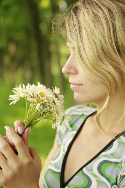 Ung flicka med en bukett blommor i naturen — Stockfoto