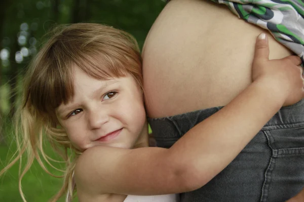 Menina perto da barriga de sua mãe grávida na natureza — Fotografia de Stock