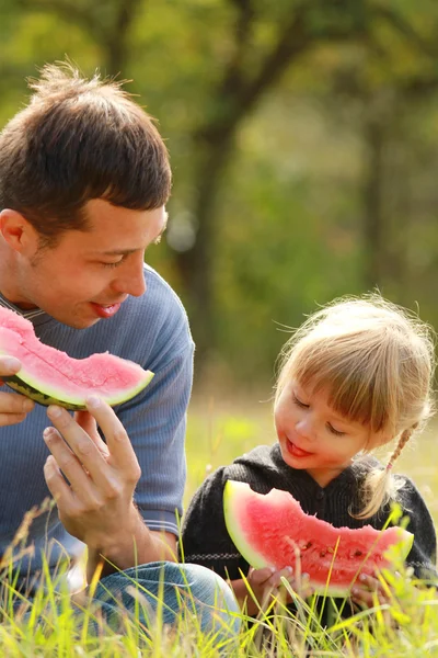 父と若い娘は自然の中でスイカを食べる — ストック写真