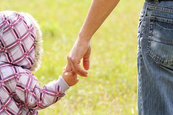 parent holds the hand of a small child
