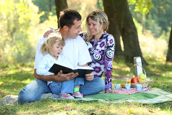 Familia joven leyendo la Biblia en la naturaleza — Foto de Stock