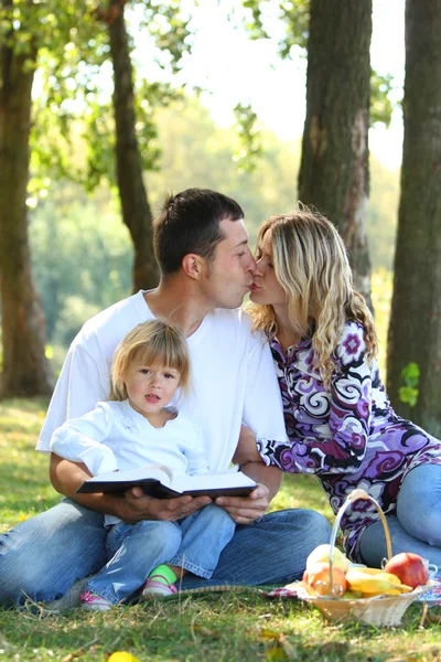 Familia joven leyendo la Biblia en la naturaleza — Foto de Stock