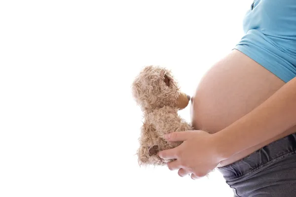 Una donna incinta con un orsacchiotto su uno sfondo bianco — Foto Stock