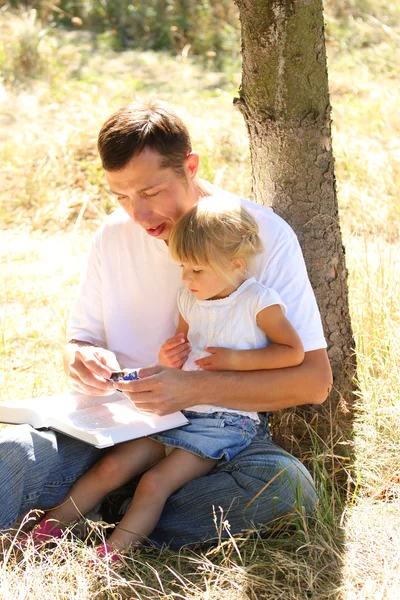 Padre joven con su pequeña hija lee la Biblia — Foto de Stock