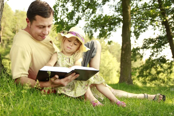 Young father with his little daughter reads the Bible — Stock Photo, Image