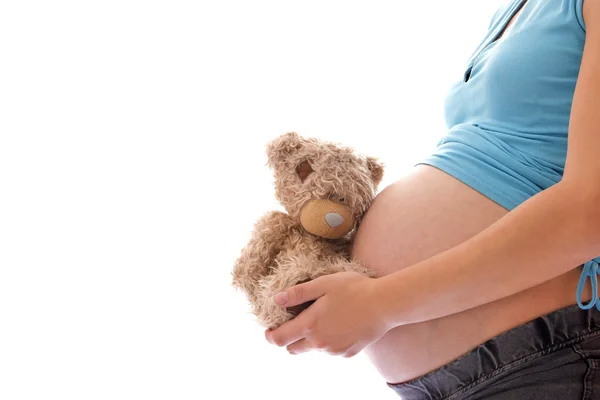 Une femme enceinte avec un ours en peluche sur fond blanc — Photo