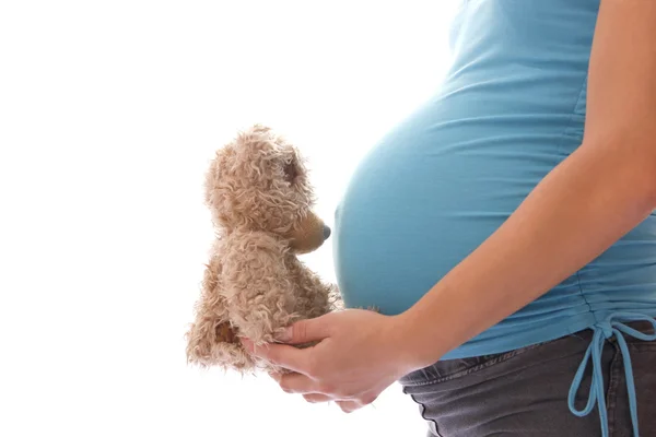 Uma mulher grávida com um ursinho de pelúcia em um fundo branco — Fotografia de Stock