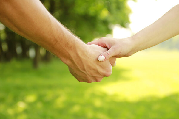 two hands of a loving couple on nature