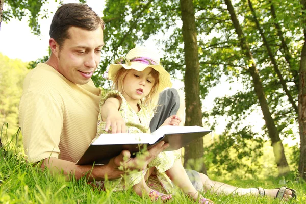 Fiatal apa kicsi lánya olvassa a Bibliát — Stock Fotó