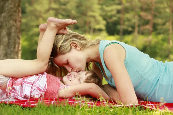 Junge Mutter und ihre kleine Tochter spielen auf Gras — Stockfoto