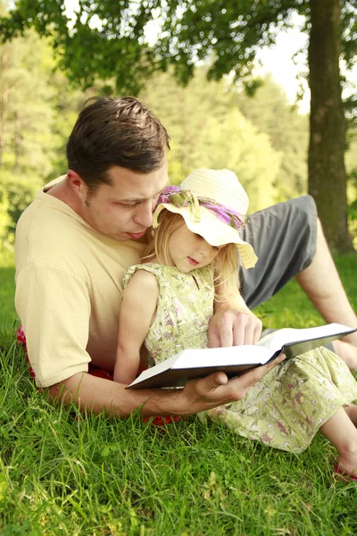 Padre joven con su pequeña hija lee la Biblia —  Fotos de Stock